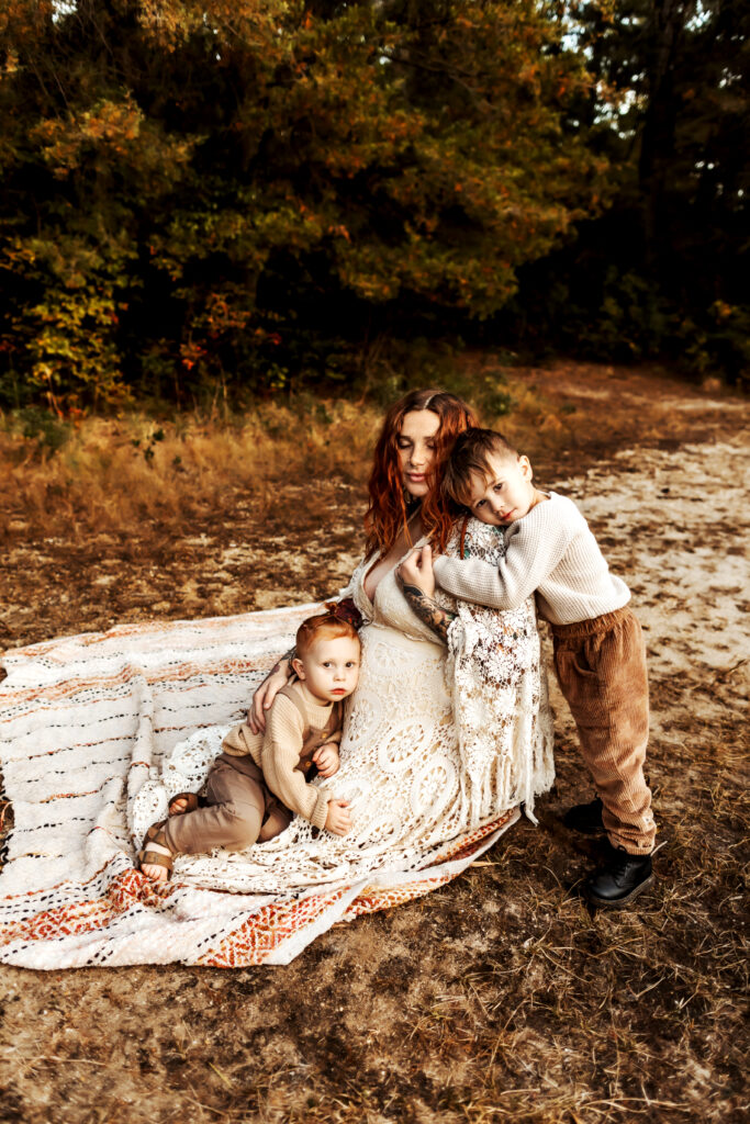 Mom getting hugs from her young boys during a maternity session in the pine barrens of NJ.