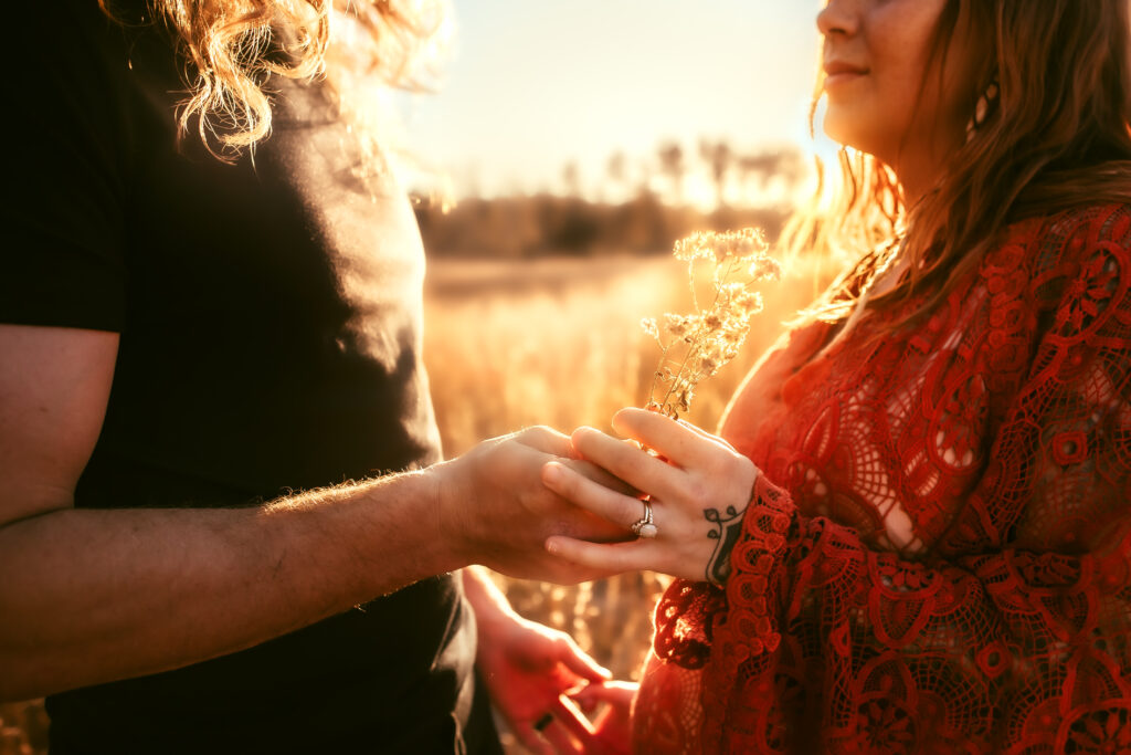 Mom and Dad during a maternity session in the pine barrens of NJ sharing a moment. Dad handing Mom wildflowers as the golden sun illuminated the flowers perfectly.